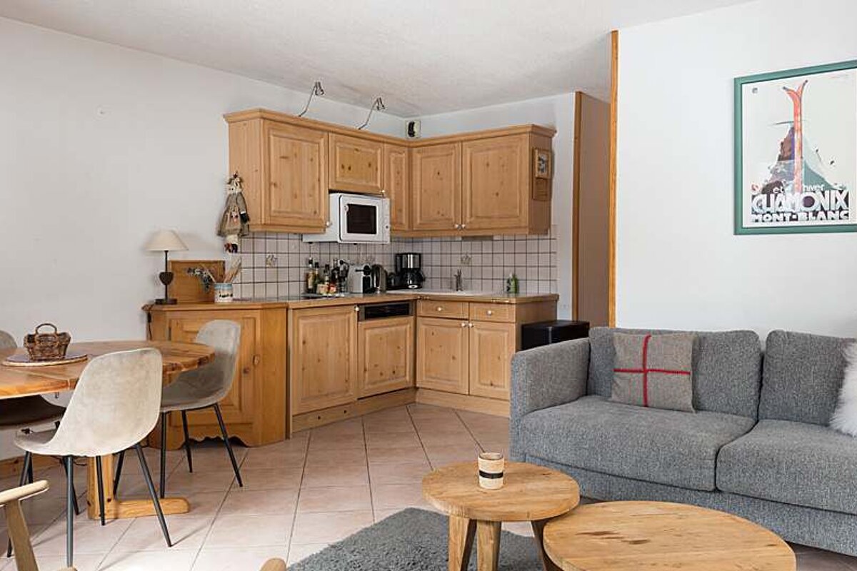 A living room with a couch and a kitchen with a poster on the wall that says mont blanc