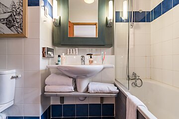 A bathroom with blue and white tiles and a sink that says ' hugo boss ' on it