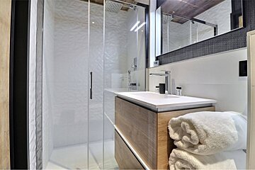 A bathroom with a sink a mirror and a walk in shower