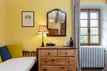 A bedroom with yellow walls and a wooden dresser