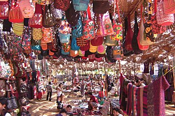 lots of coloured fabircs, bags & hippy garments hanging up