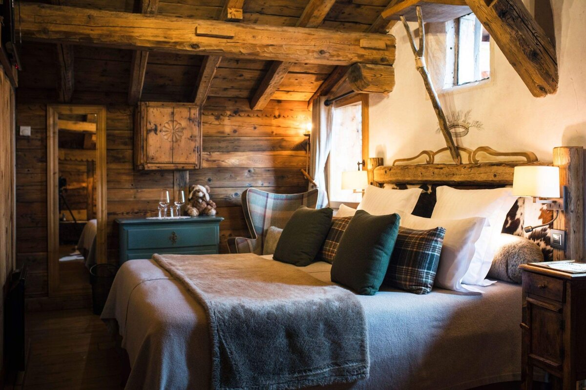 A cozy, rustic wooden chalet bedroom with a large bed, plaid accents, and warm lighting creates an inviting, comfortable retreat.