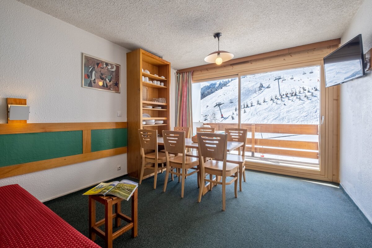 A room with a table and chairs and a television