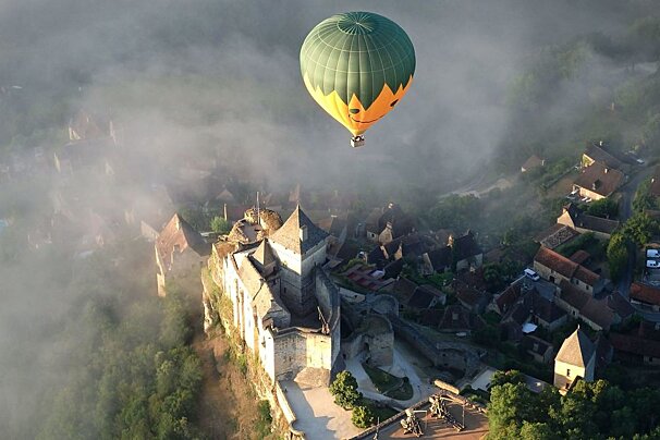 a hot air balloon above the chateau de beynac
