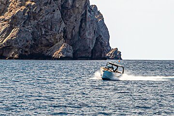 A boat is floating in the ocean with a mountain in the background