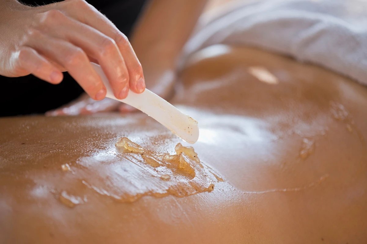 A woman getting a massage with a spatula on her back