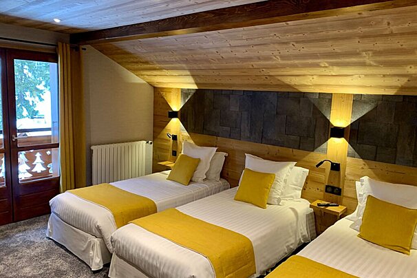 A hotel room with three beds and a balcony