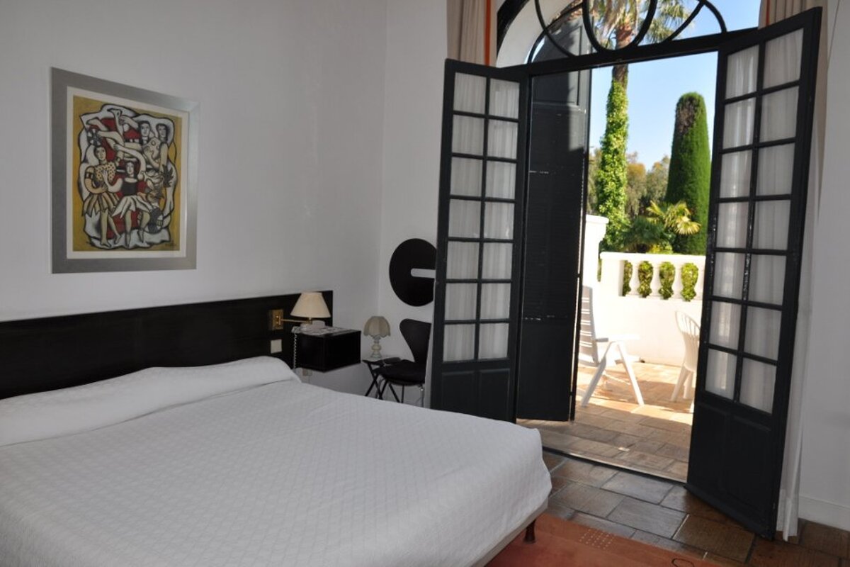 A bedroom with a large bed and a painting on the wall