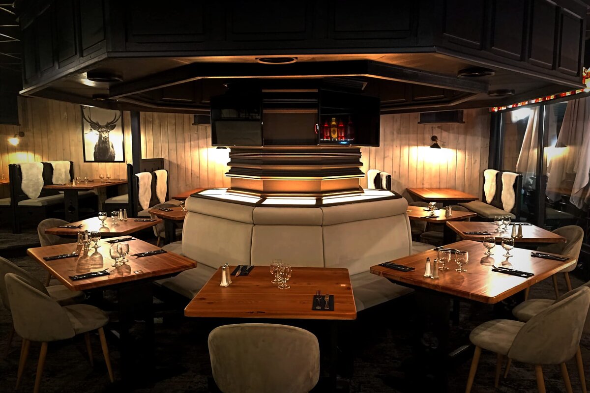 A dining room with tables and chairs and a deer picture on the wall