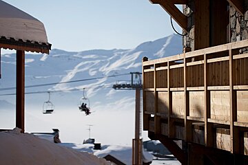 A ski lift is visible in the distance behind a wooden balcony