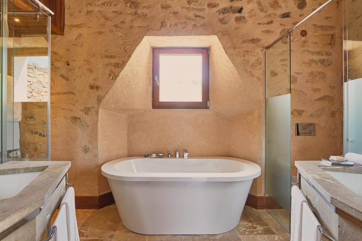 A bathtub in a bathroom with a window above it