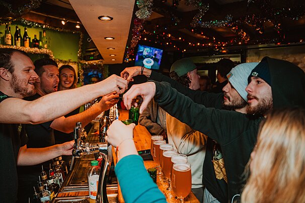 A group of people are gathered at a bar drinking beer
