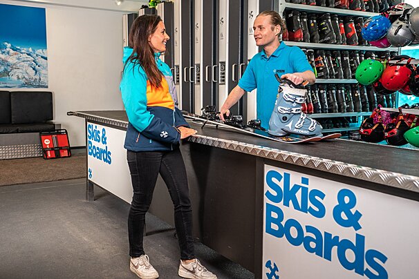 A woman is getting skis and boards from a man