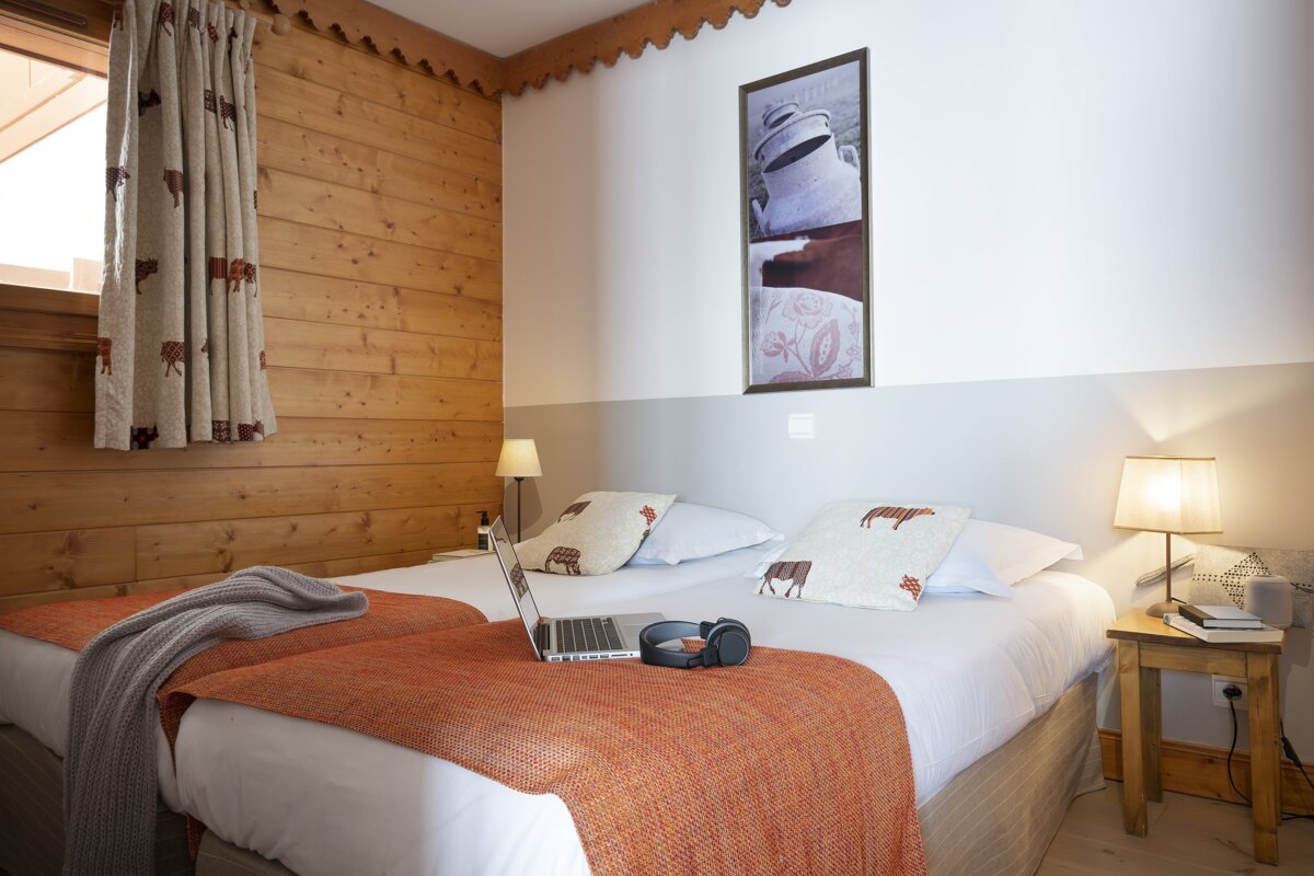 A bedroom with two beds and a laptop on the bed