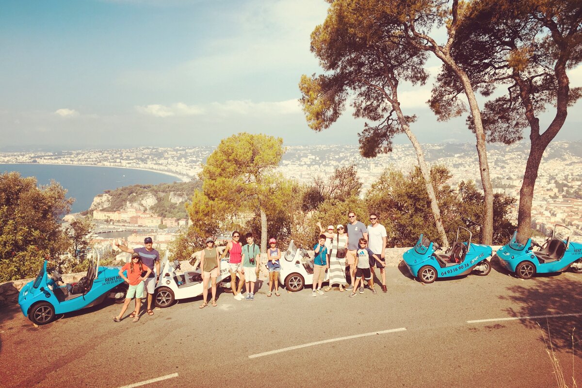 A group of people are posing for a picture in front of a car that says ' riviera ' on it