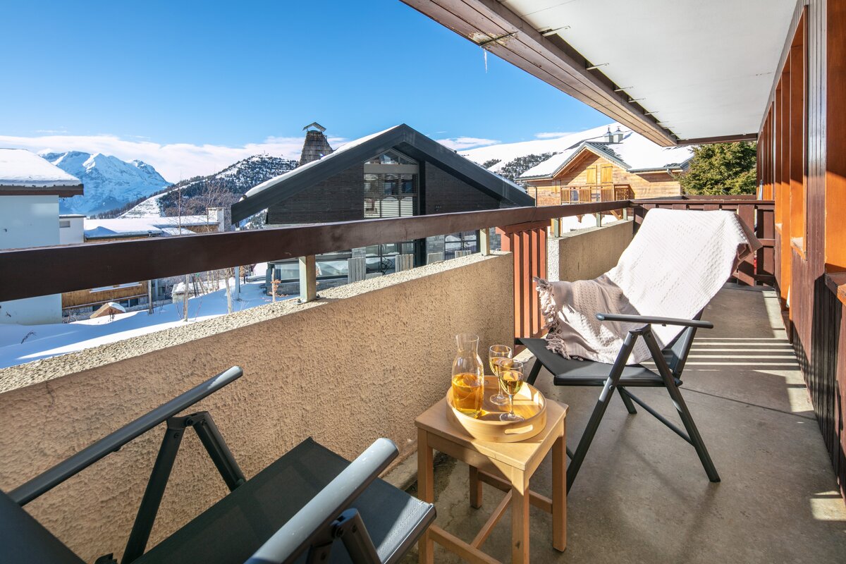 A balcony with a chair and two glasses of champagne