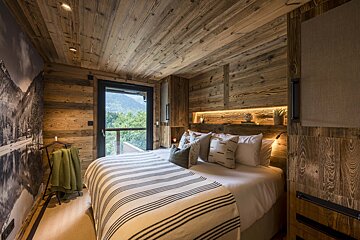 A bedroom with wooden walls and a bed with a striped blanket