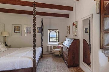 A bedroom with a four poster bed and a desk