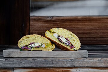 A sandwich is cut in half on a wooden cutting board