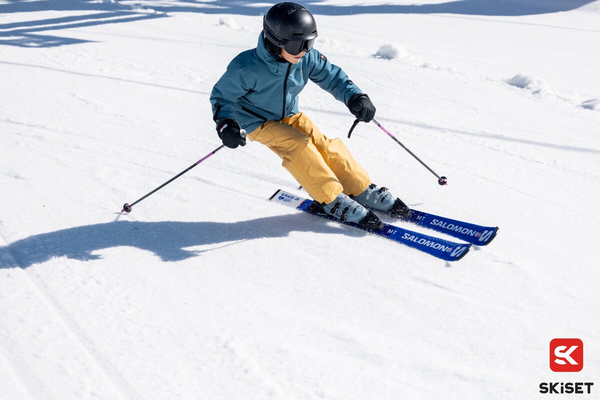 A person is skiing down a snowy slope with skis that say salomon on them