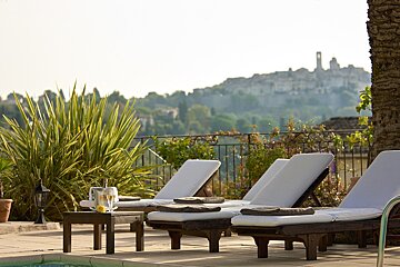 A bottle of champagne sits on a table next to some lounge chairs