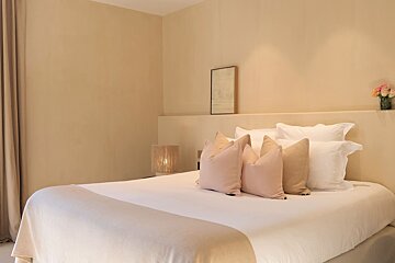 A bed with white sheets and pillows in a bedroom