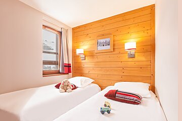 A bedroom with two beds and a picture on the wall