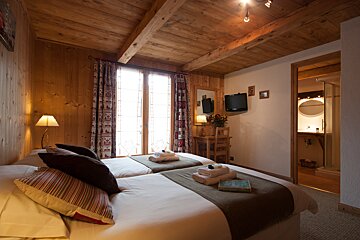 A bedroom with two beds and a television on the wall