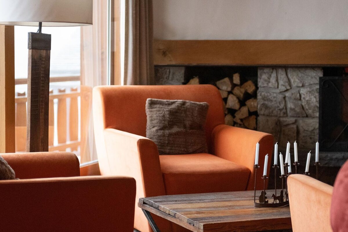 A living room with orange chairs and a fireplace