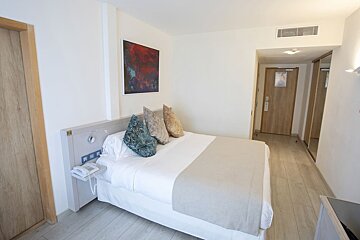 A hotel room with a bed and a painting on the wall