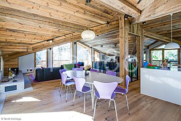 A dining room with purple chairs and a white table