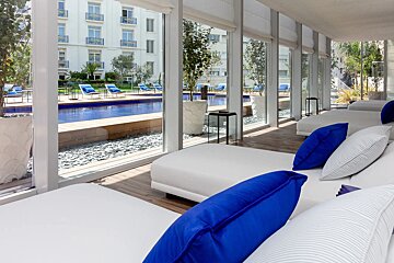 A room with blue pillows and a pool in the background