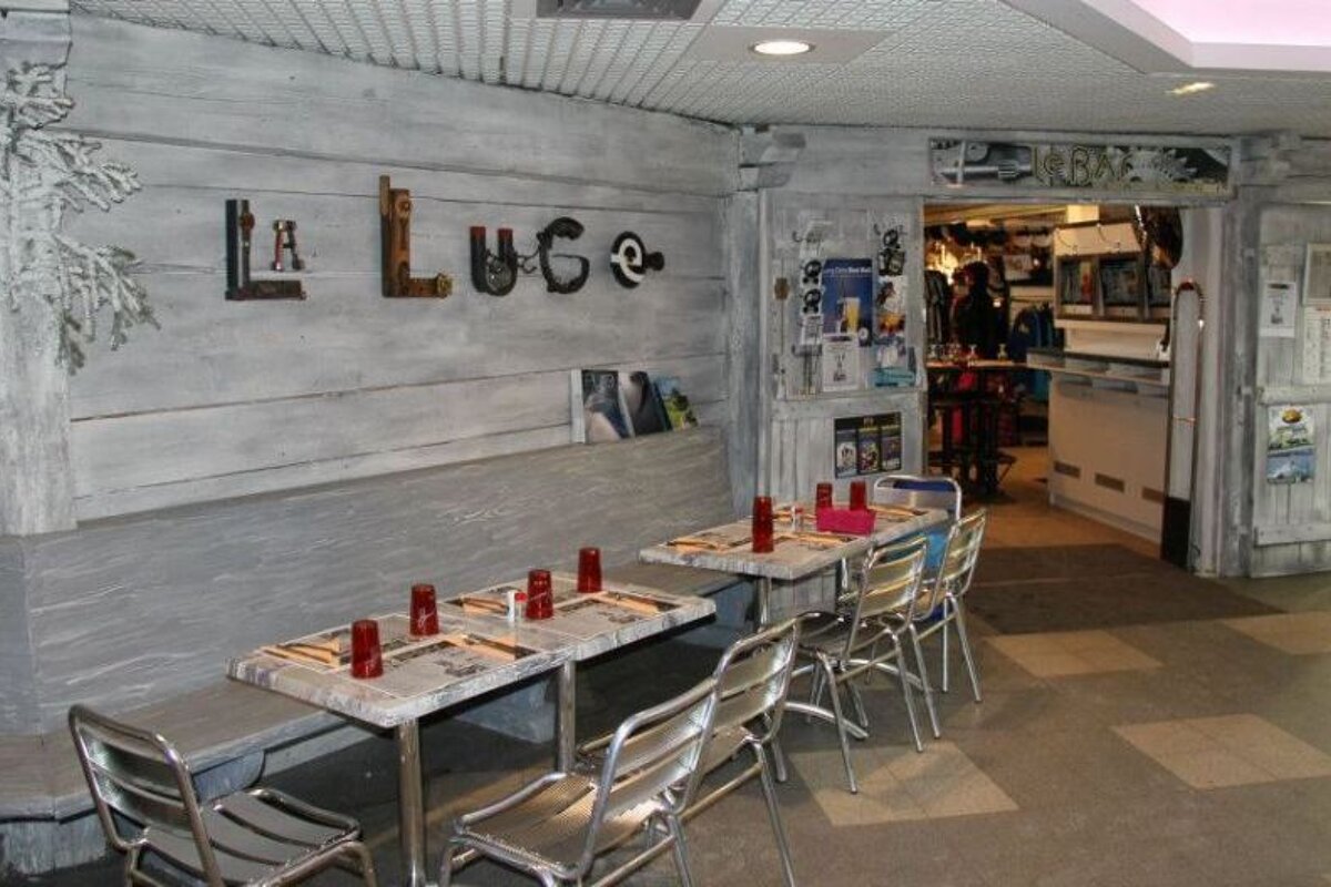 A restaurant with tables and chairs and the word lugo on the wall