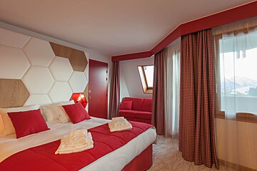 A hotel room with a red bed and a red chair
