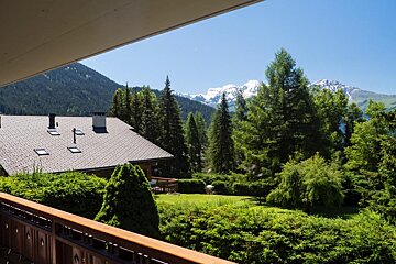 A balcony with a view of mountains and trees