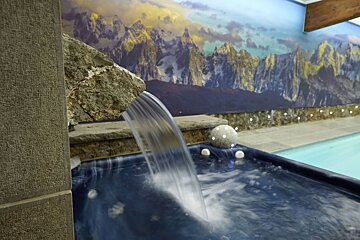 A waterfall in front of a painting of mountains