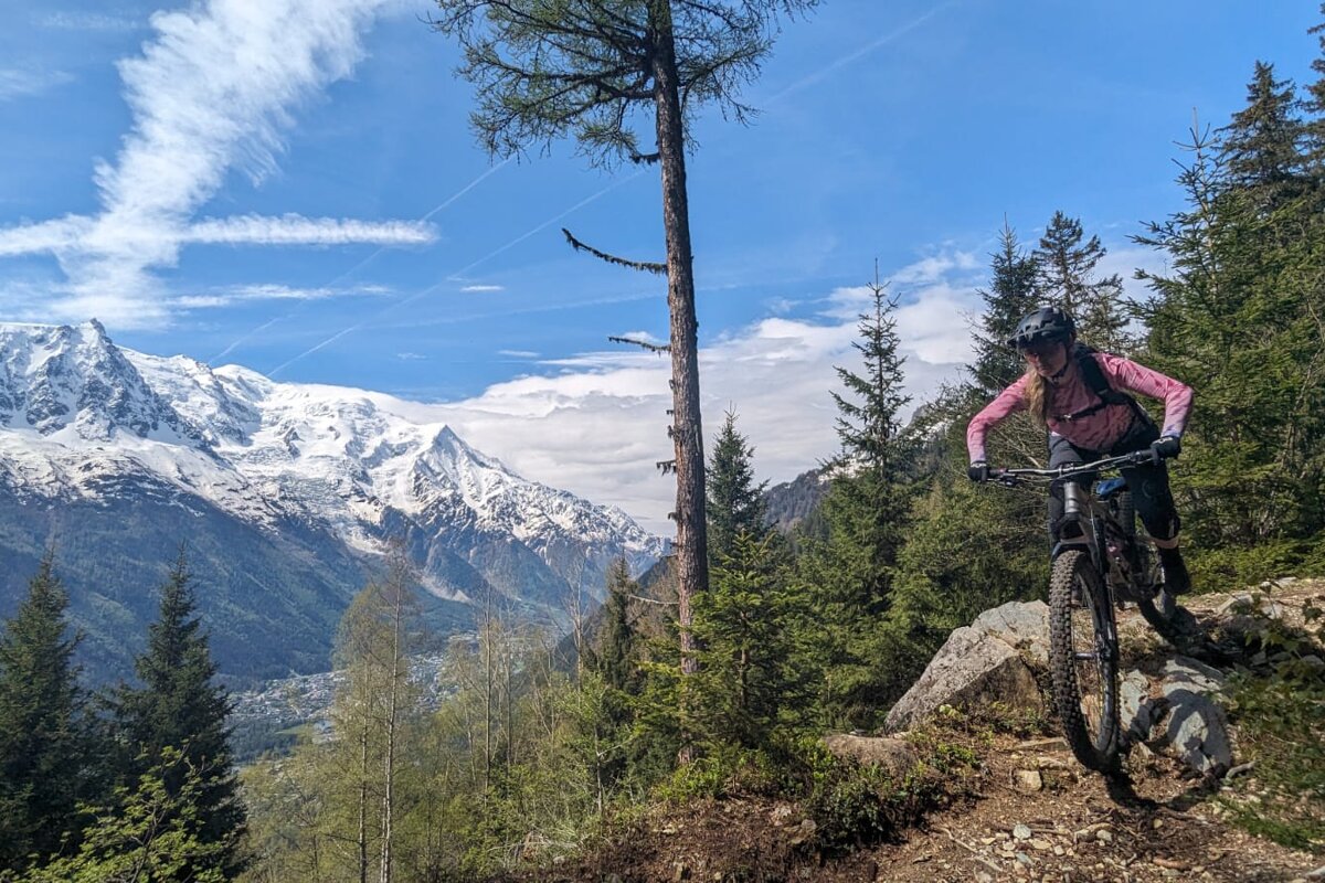 A person riding a bike on a trail with mountains in the background