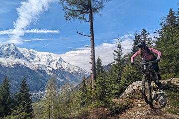 A person riding a bike on a trail with mountains in the background