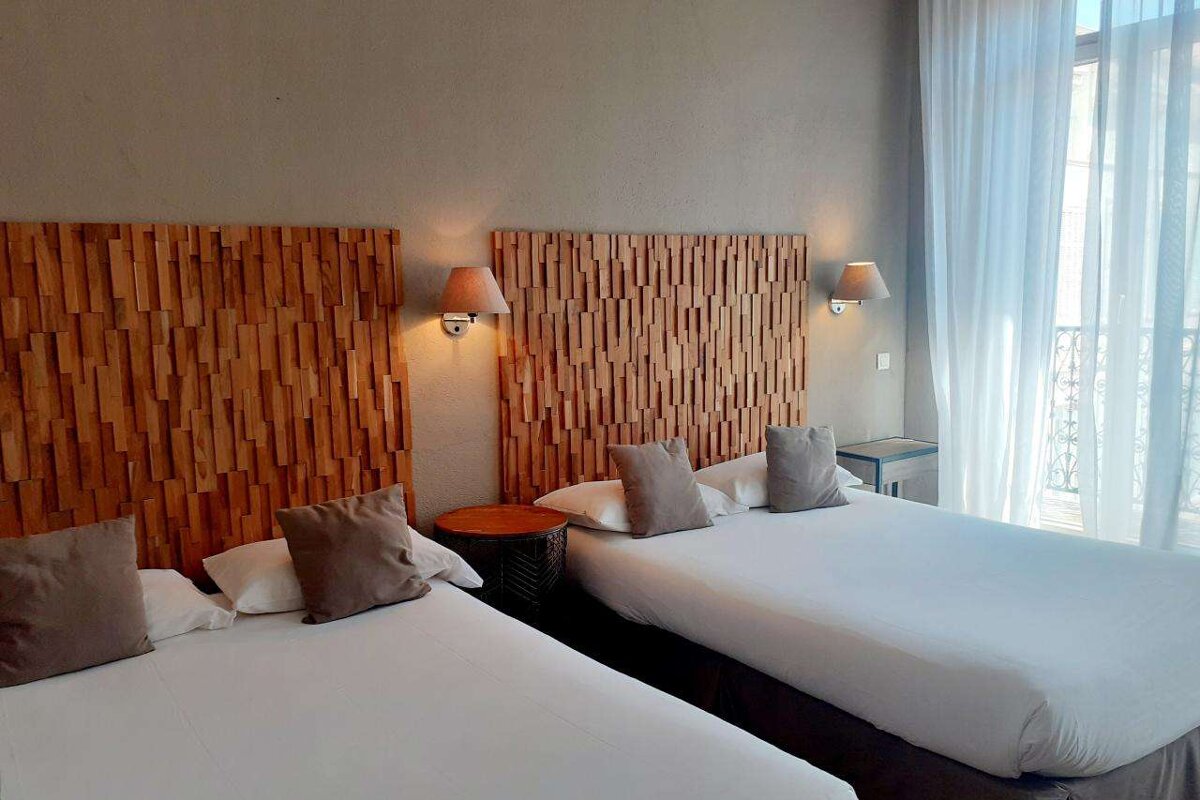 A hotel room with two beds and a wooden headboard