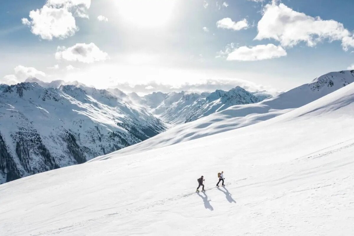 Two people skiing down a snow covered mountain
