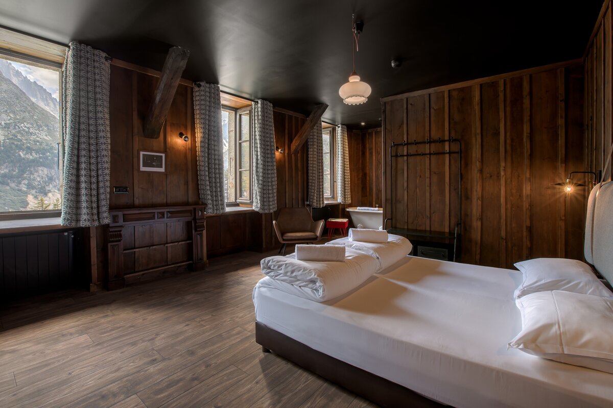 A bedroom with wood paneling and a bed with white sheets