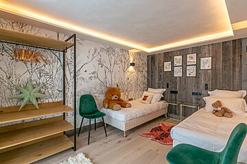 A bedroom with two beds and a teddy bear on the bed