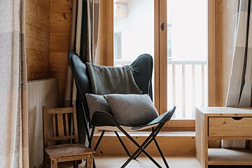 A chair with a blanket on it sits in front of a window