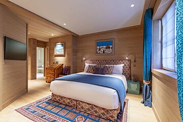 A bedroom with a painting on the wall above the bed