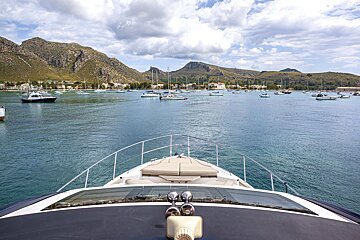 A boat is floating in a body of water with mountains in the background