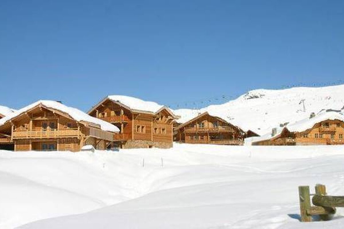 A row of wooden houses sitting on top of a snow covered hill