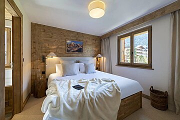 A bedroom with a painting on the wall above the bed