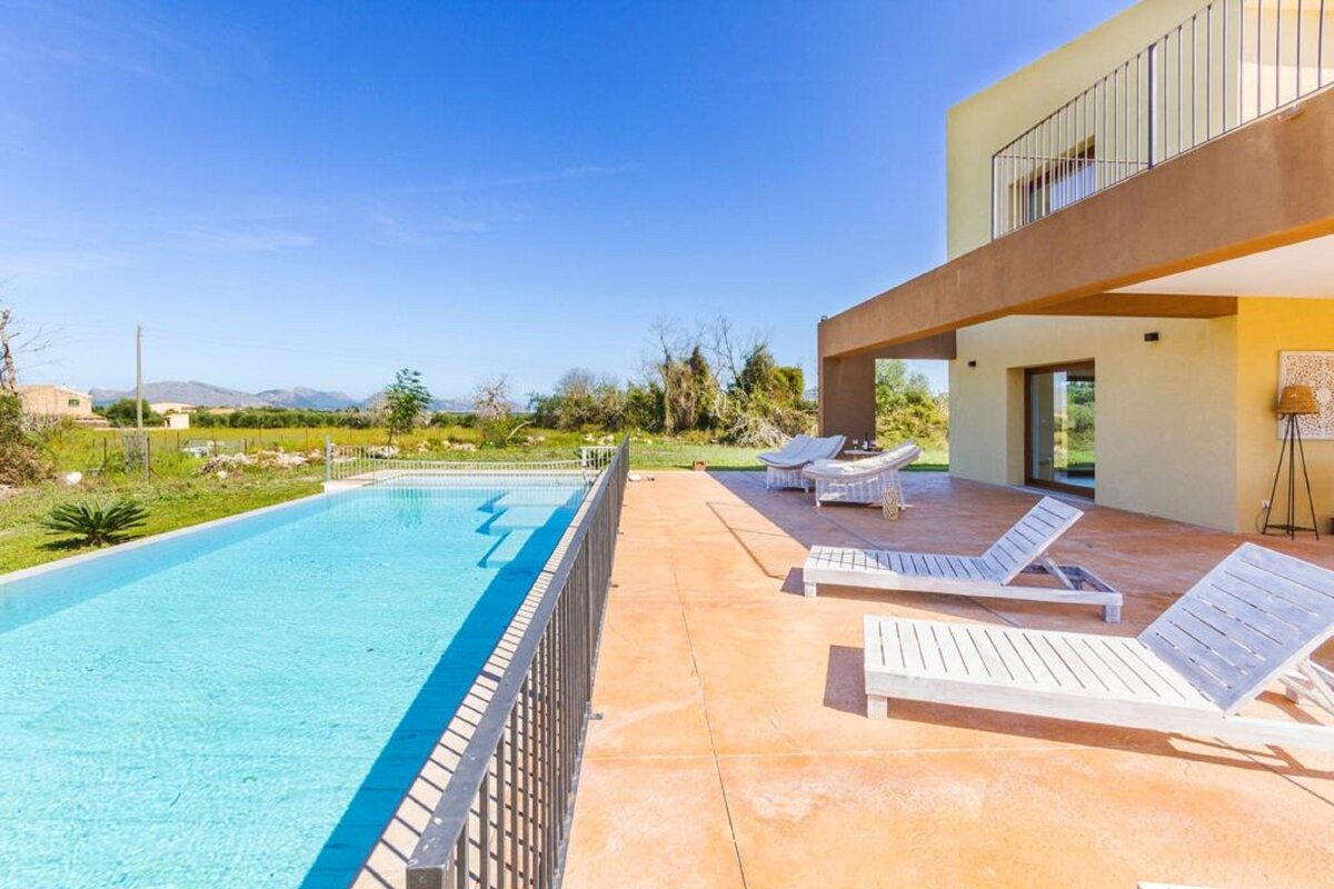 A large swimming pool is surrounded by chairs and a fence