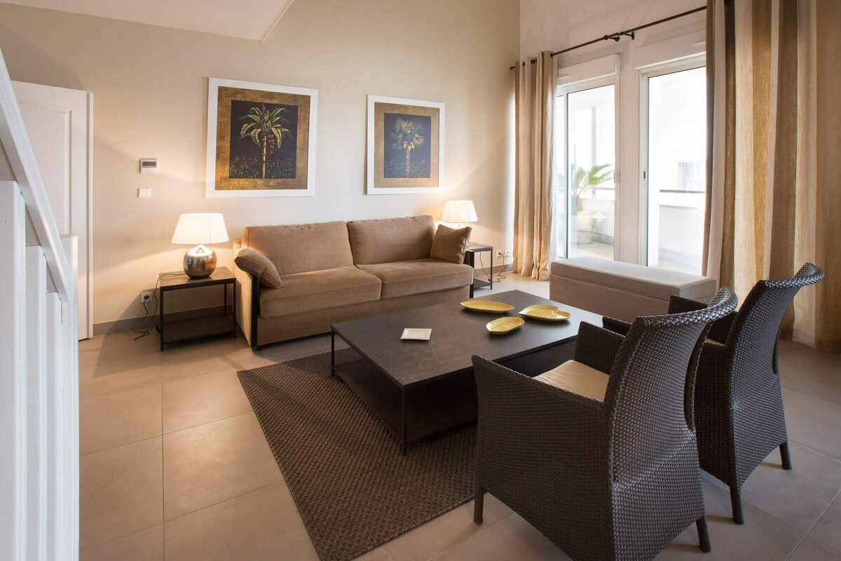 A living room with a couch and chairs and two paintings on the wall