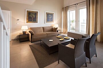 A living room with a couch and chairs and two paintings on the wall